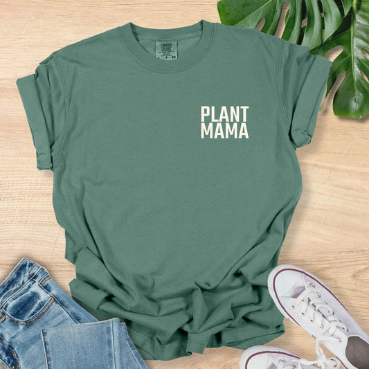 Green t-shirt with 'PLANT MAMA' text on a wooden surface with jeans and sneakers.