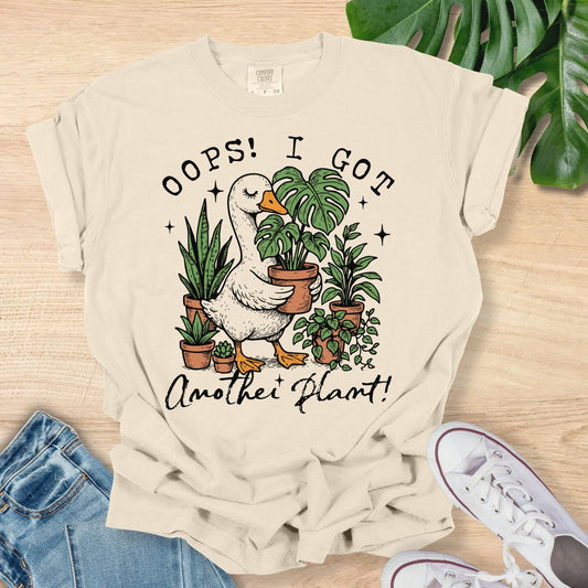 Beige t-shirt with green succulent design and text on a wooden surface with plants and shoes.